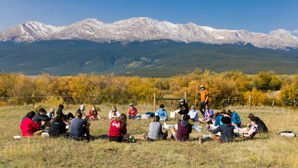 A circle of students with mountains in the background